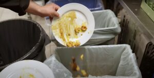 Assiette de restes alimentaires vidée dans un bac de collecte des matières organiques en entreprise
